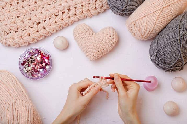 Closeup of hands knitting pink hearts, Quirky Valentine's gift