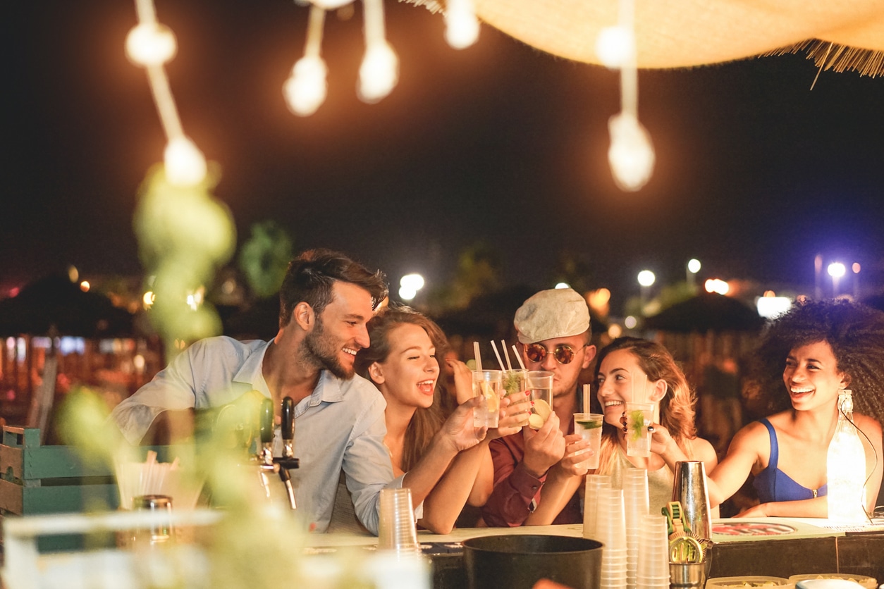A happy group of friends cheering and drinking cocktails during happy hour.
