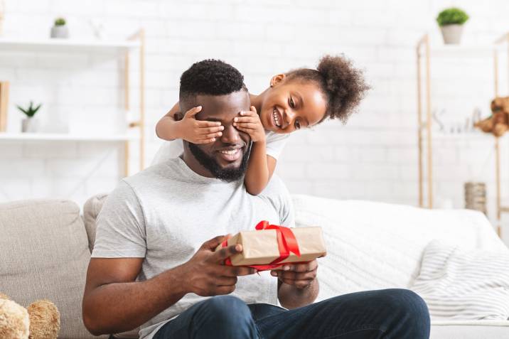 little girl surprising her dad with a father's day gift