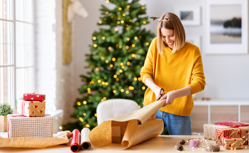happy young woman wrapping Christmas gift