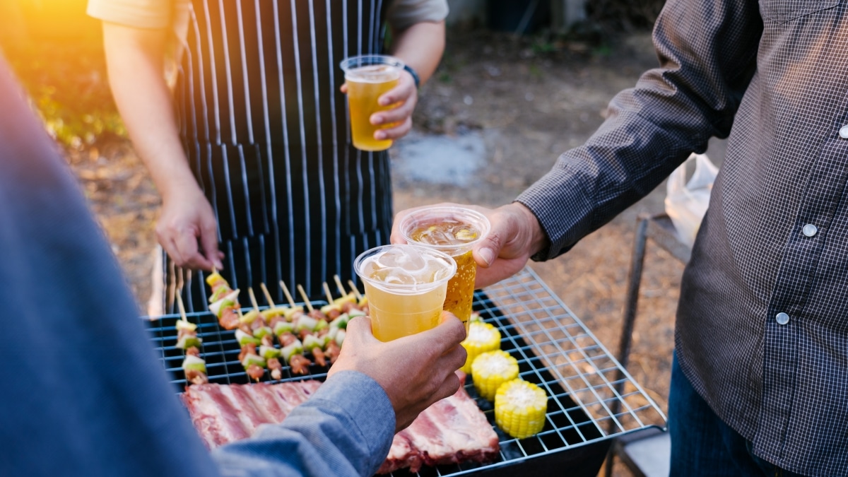 Father and sons cooking on the barbecue grill while having drinks