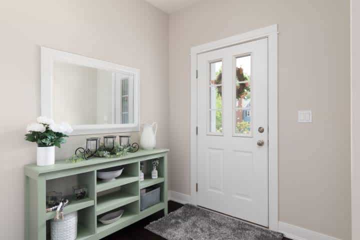 A cozy entryway with cream walls and a green console table.