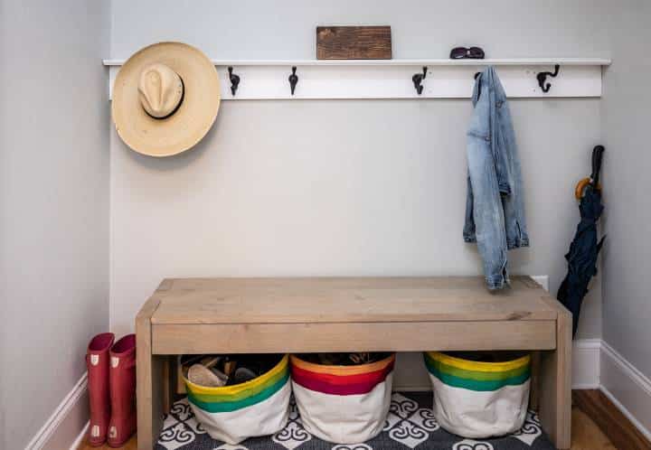 A small entrance mudroom with hooks for hanging jackets, hats, and coloured buckets