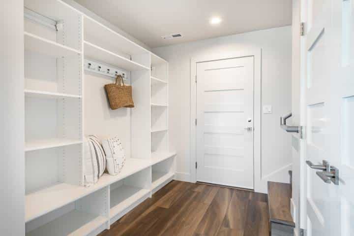 pantry and mudroom with white walls shelving hardwood floor