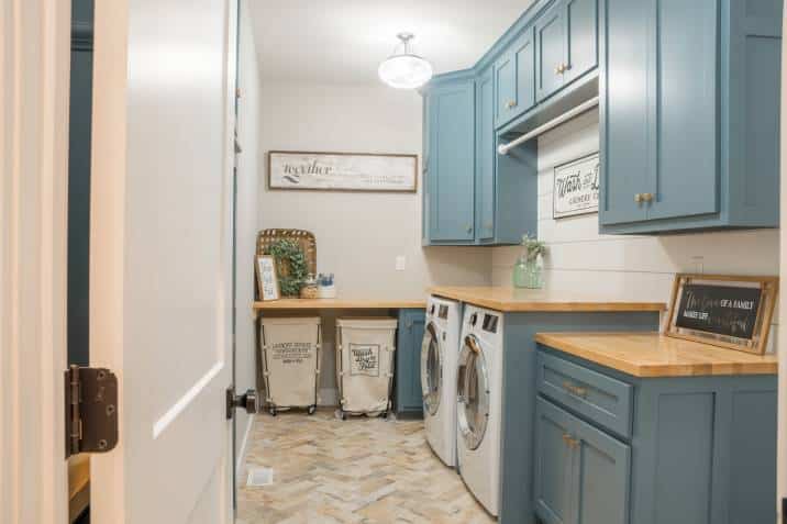 Farmhouse style laundry room, rolling carts, signs, blue cabinets.