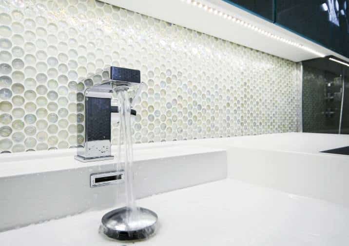modern designer laundry sink with running water and mosaic wall, round penny-sized tiles