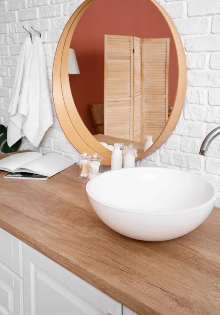 round laundry sink, wooden countertop and round mirror frame 
