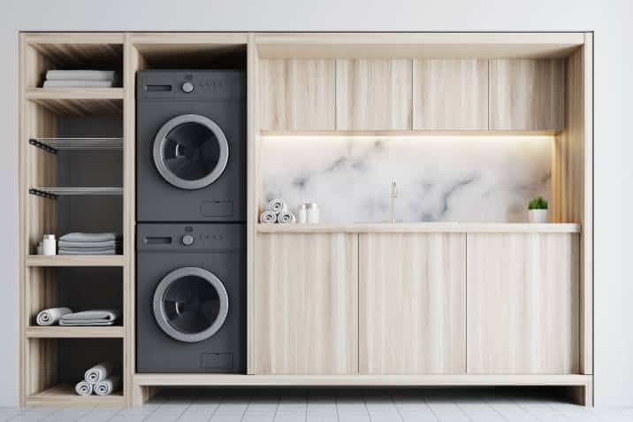 laundry room interior with wooden countertops, a closet and built in washing machines, one washing machine stacked on top of the other