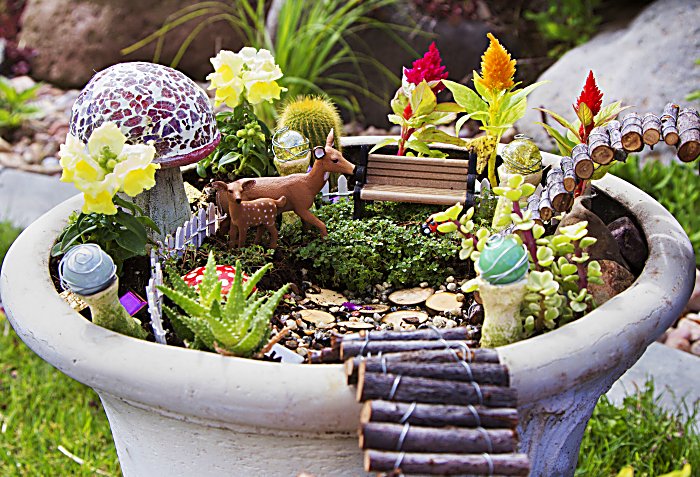 Fairy garden with deer, gazing balls and mushrooms in a flower pot