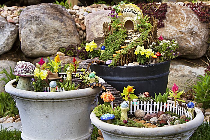 Fairy garden in a flower pot with walking path, wooden bridges and a fairy house.