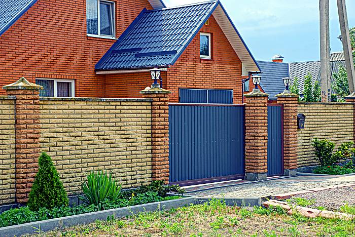 Long modern brown fence made of bricks and iron on the street in front of the road