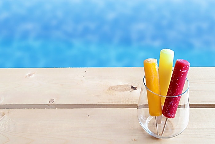 Frozen ice lollies in a glass by a swimming pool