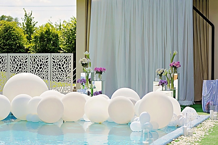 Decorations for the wedding ceremony by the pool with blue water.