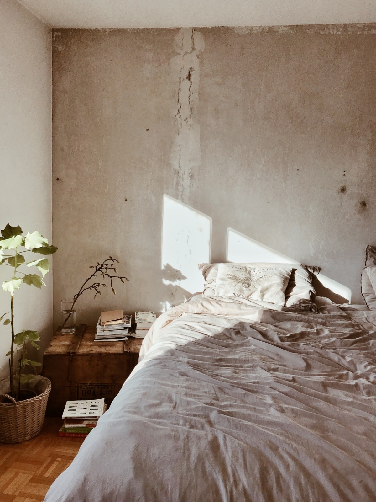 Bedroom with disheveled bed and concrete wall