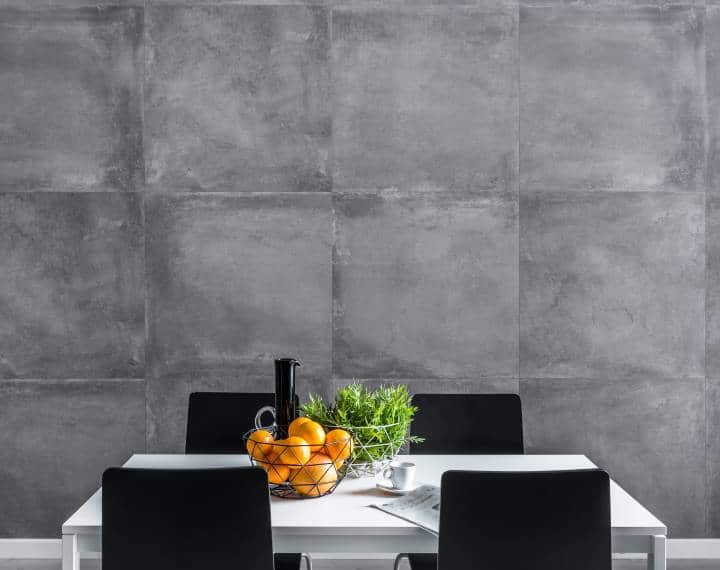 Dining room with concrete wall, white table and black chairs