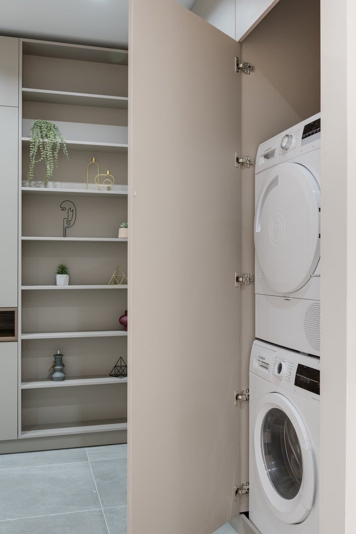 Cupboard door opens to reveal dryer stacked on washing machine