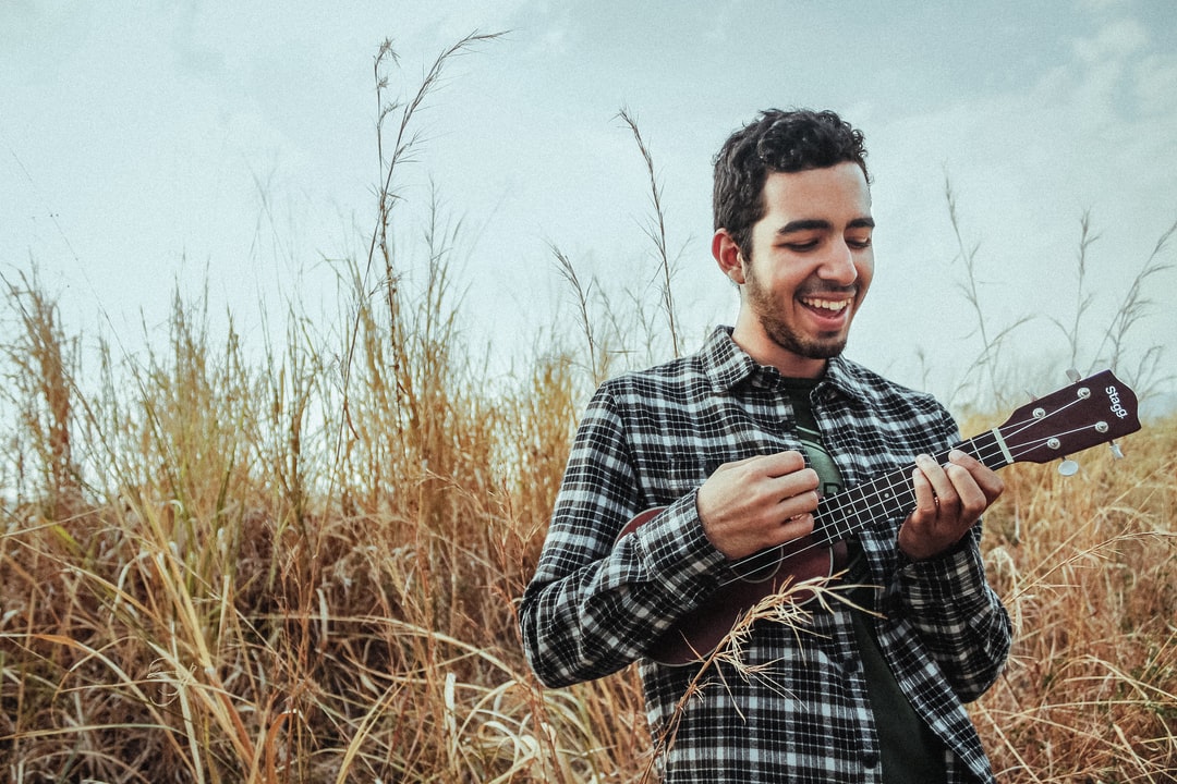 a man playing a ukelele in a field