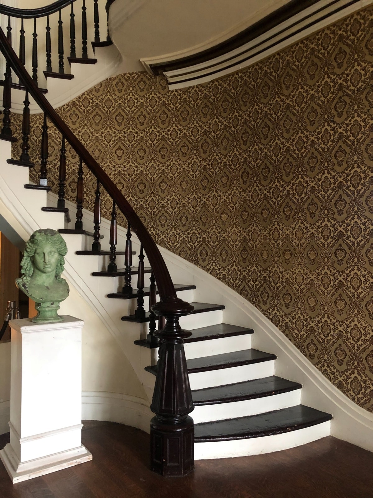 black and white curved staircase with a wallpaper backdrop