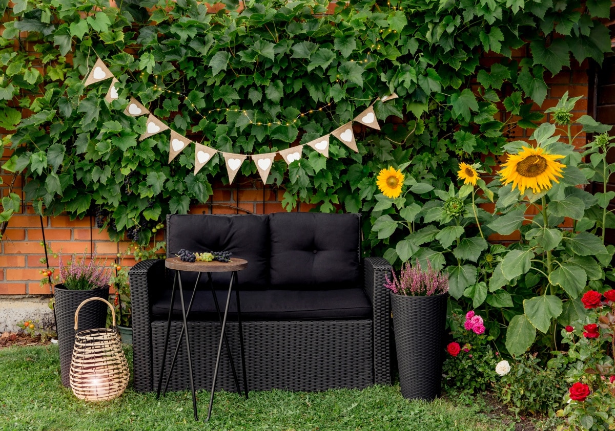 Black modern garden chair and metal wire side table surrounded by greenery