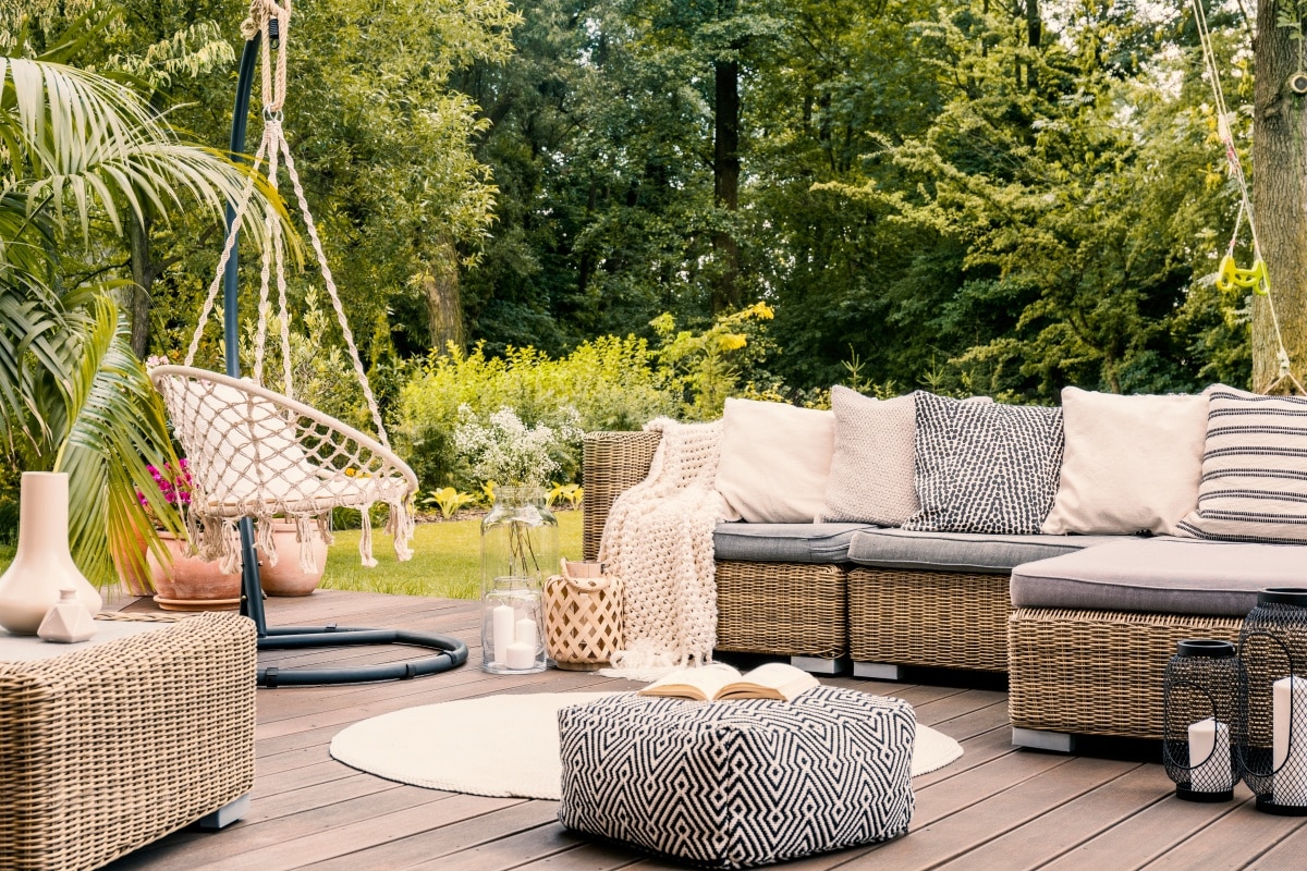 black and white pouf in the middle of a bright terrace with a rattan corner sofa and hanging chair