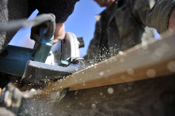 two carpenters cutting wood