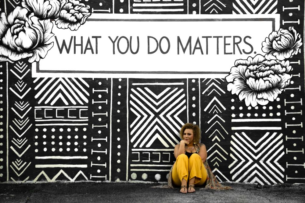 monochromatic mural saying "what you do matters" with woman sitting in front