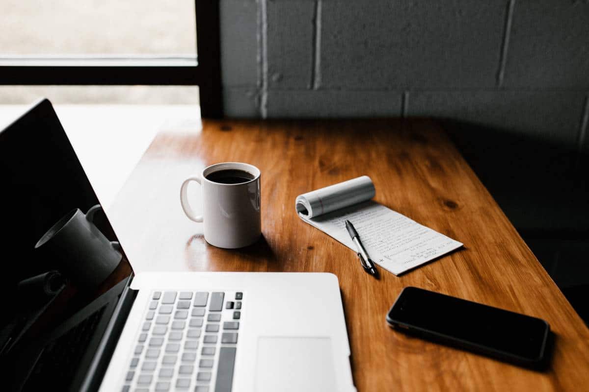 work desk with laptop, notepad, and mobile phone