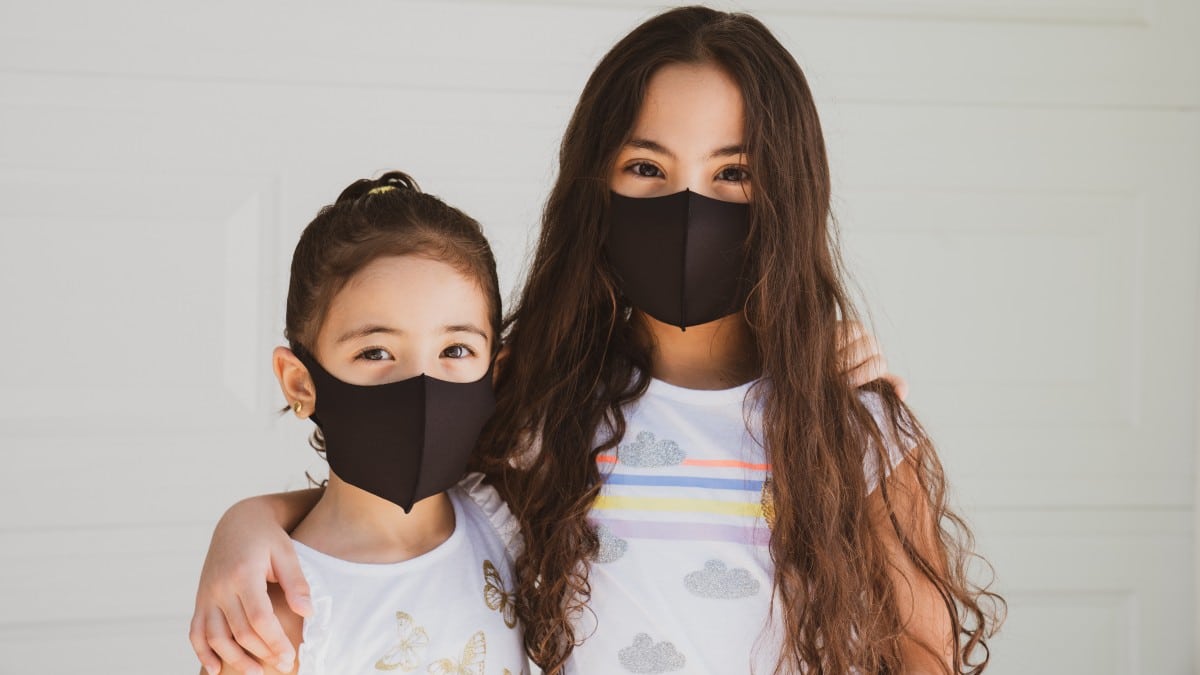 Two young girls wearing black cloth masks