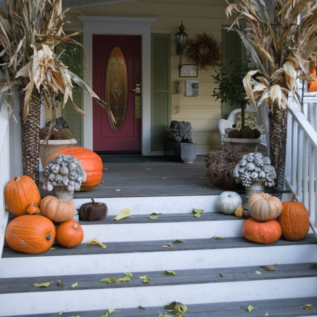 An entryway decorated with a simple wreath and some pumpkins