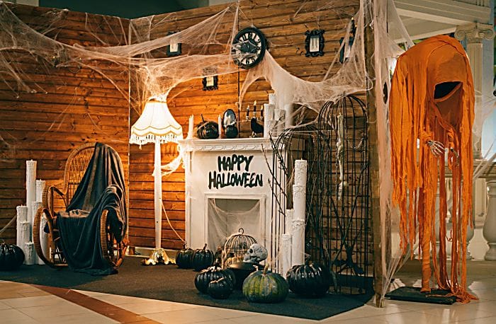 Photo area for Halloween with festive attributes. Fireplace, pumpkins, candles, skulls, bones, candles, chair, monsters decorations for Halloween indoors.