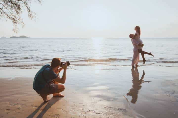 photographer taking pictures of a couple by the beach