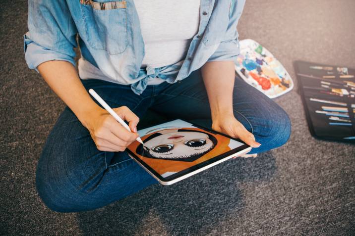 woman artist illustrator drawing a custom portrait on digital tablet with stylus