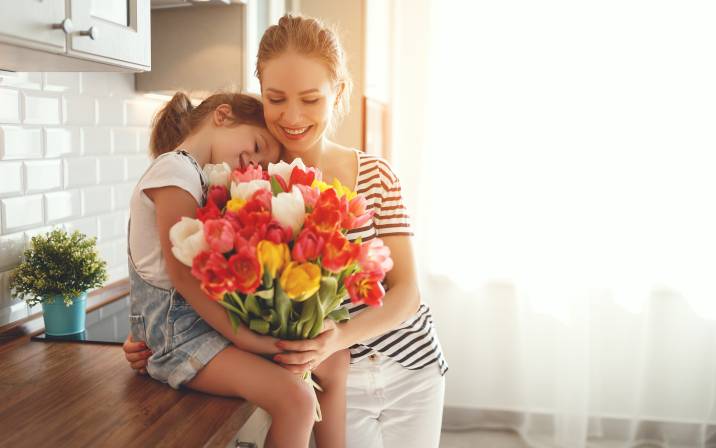little girl gifting her mom with flowers