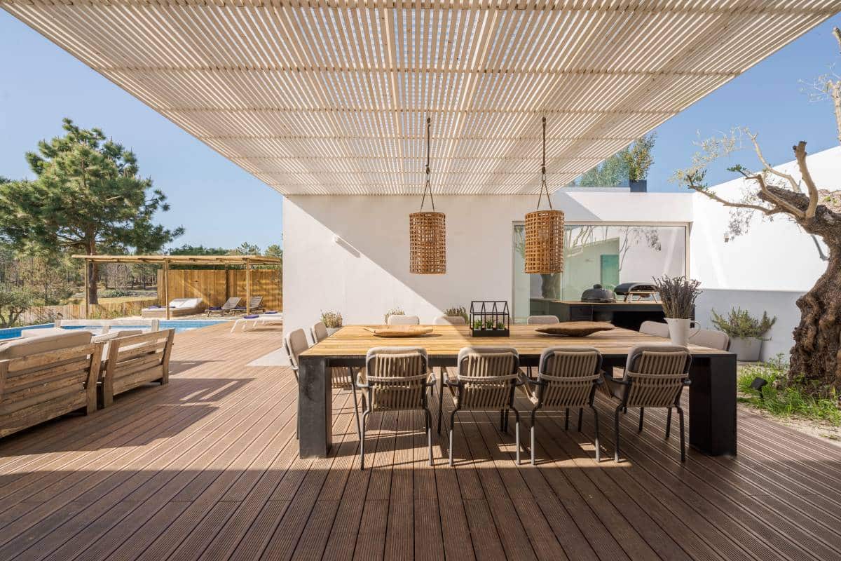 Modern villa with pool. Covered deck with wooden dining table and chairs 