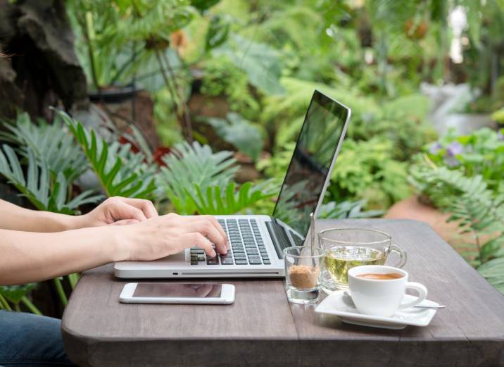 woman using laptop in garden coworking space