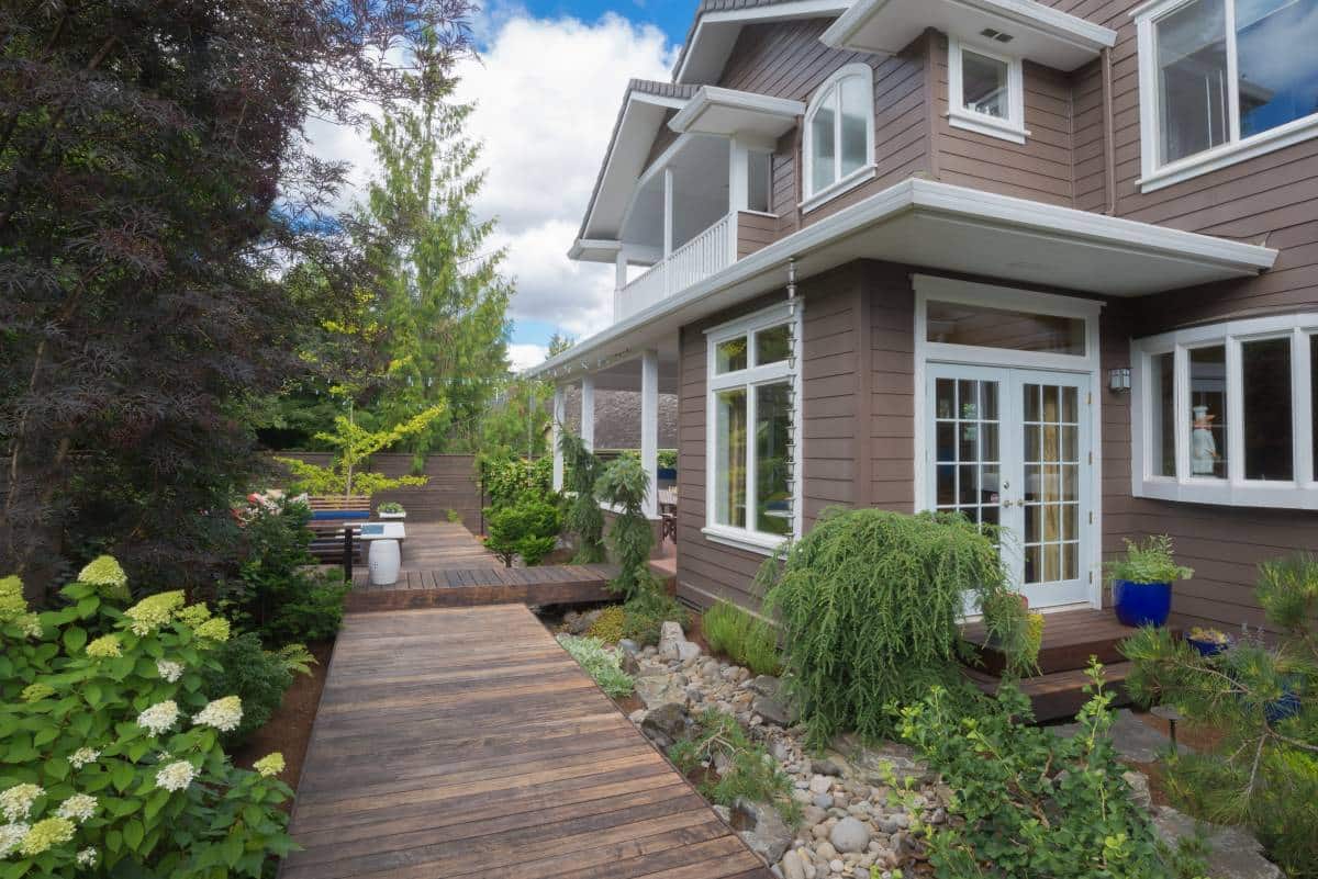 white-framed windows and doors in Hamptons-style house, a narrow deck goes past double doors in the backyard 