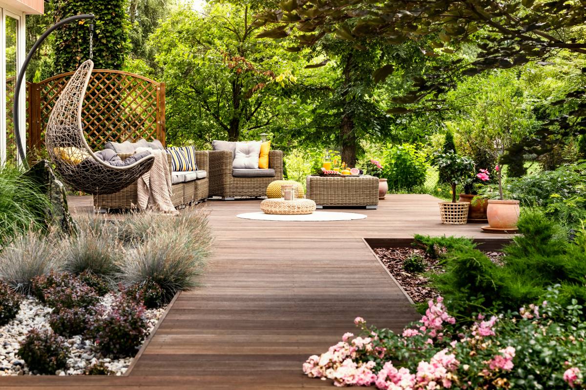 beautiful wooden terrace with garden furniture surrounded by greenery on a warm, summer day