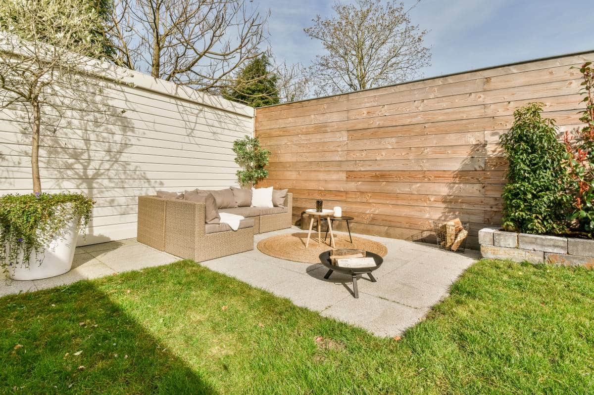 neat paved patio with sitting area and small garden near wooden fence