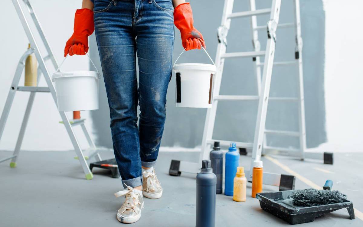 Female house painter, contractor holds pails with paints