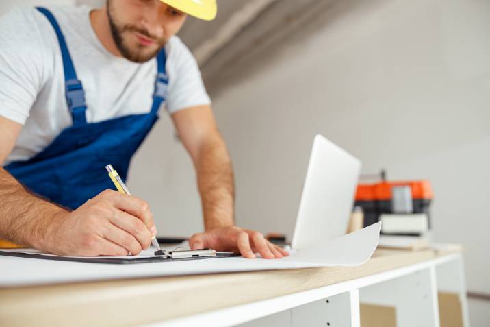 male contractor writing down business ideas and handyman skills to learn
