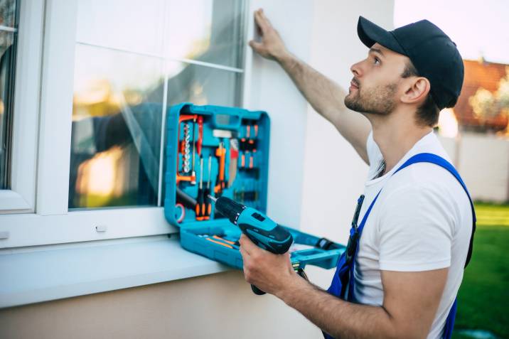 handyman installing or repairing window outdoors