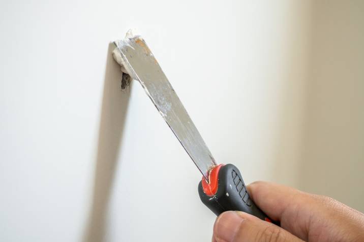 repairing a crack on a white drywall, plasterboard with spatula
