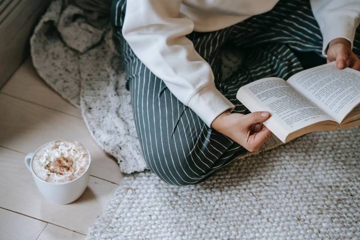 girl reading a book while drinking hot cocoa