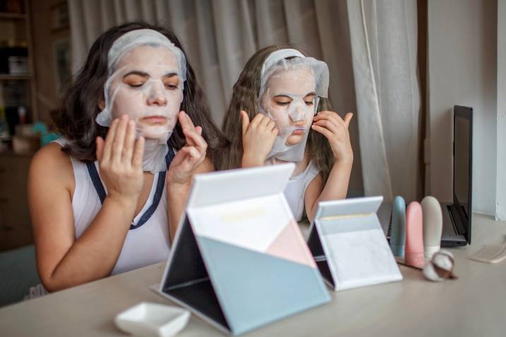 a mother and daughter putting a sheet mask on