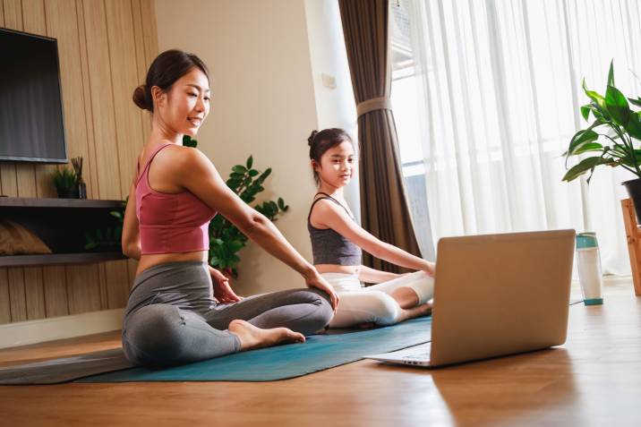 a mother and daughter practicing yoga in the living room