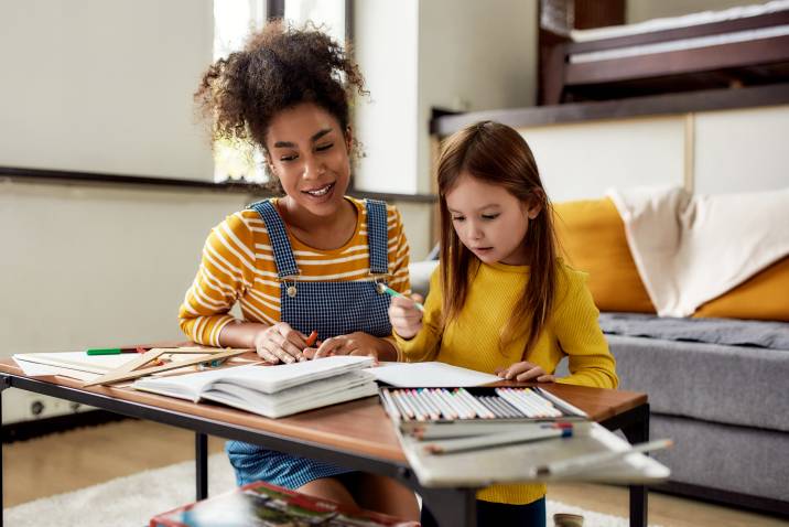 babysitter teaching a little girl how to write