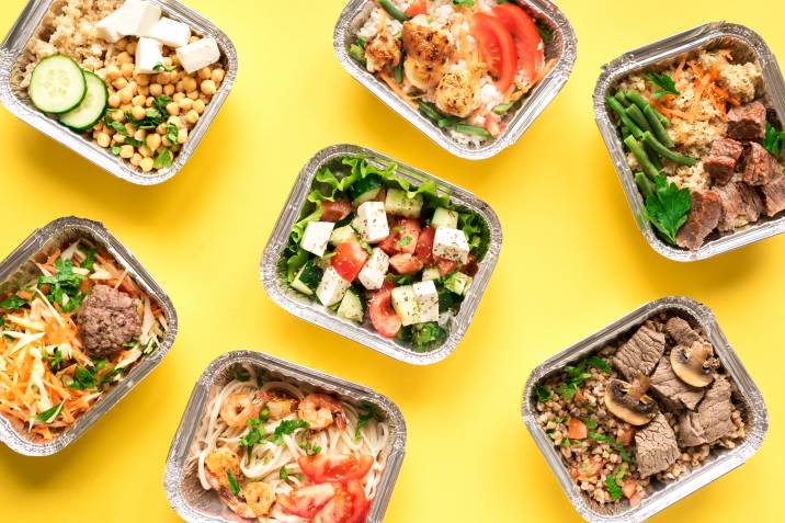 meal prep trays laid out on a yellow table