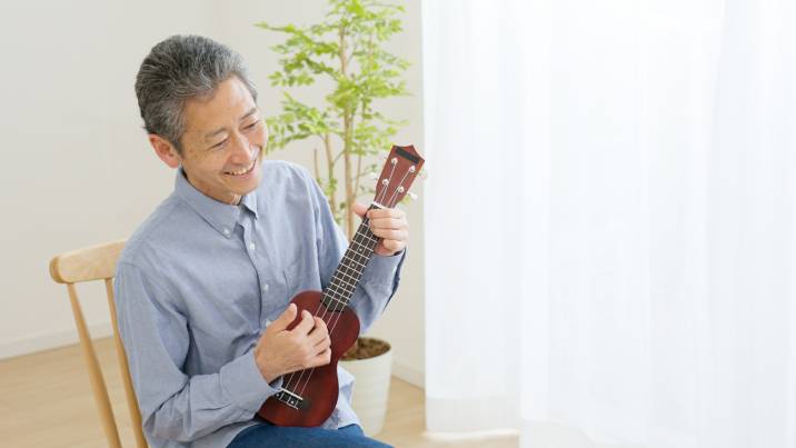 retired senior man teaching ukulele lesson