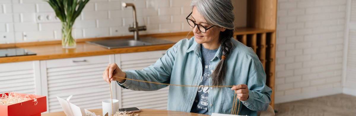 retired grey-haired woman wrapping gifts to deliver to customers