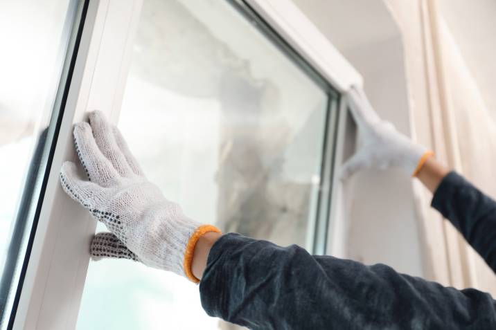 Worker installing plastic window indoors